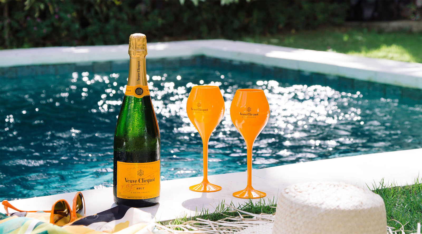 Bottle of Veuve Clicquot champagne and glasses poolside - an example of consistent brand assets